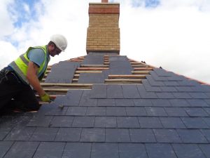 Roofer replacing slates on a pitched roof for Kingsley Roofing.