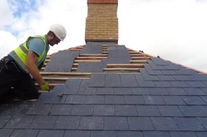 Roofer replacing slates on a pitched roof for Kingsley Roofing.
